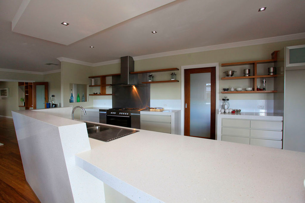 Open concept kitchen - large transitional galley medium tone wood floor and brown floor open concept kitchen idea in DC Metro with a drop-in sink, flat-panel cabinets, beige cabinets, quartz countertops, white backsplash, glass sheet backsplash, stainless steel appliances and an island