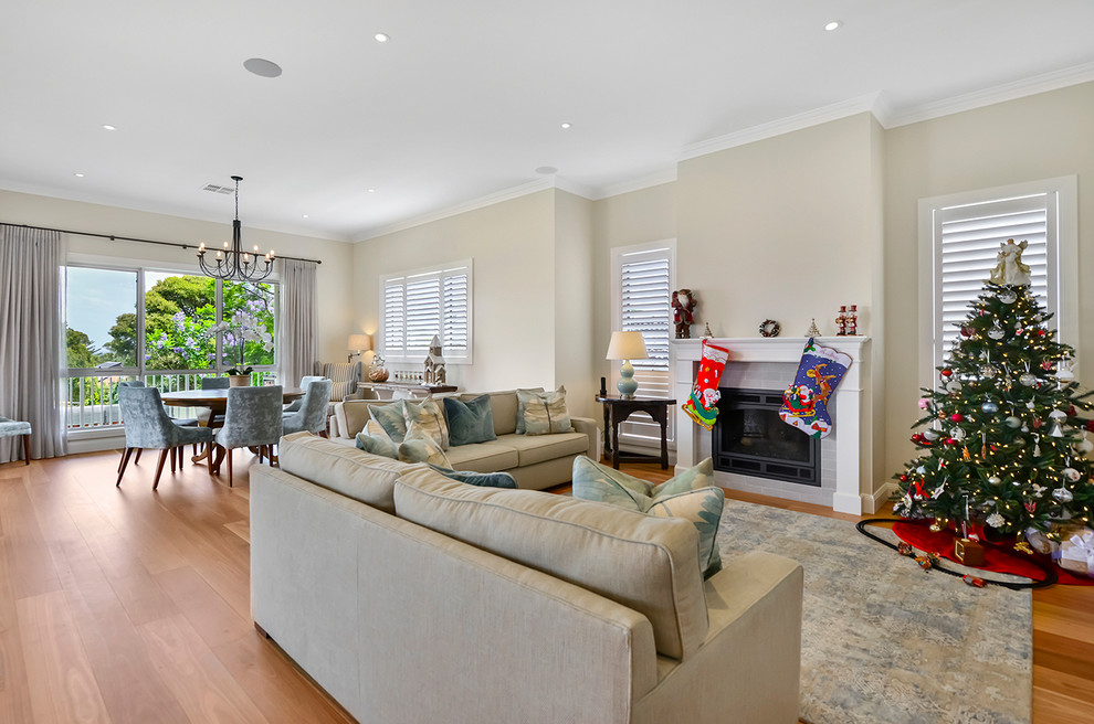 Inspiration for a large contemporary open concept family room in Sydney with a game room, beige walls, light hardwood floors, a standard fireplace, a wood fireplace surround and brown floor.