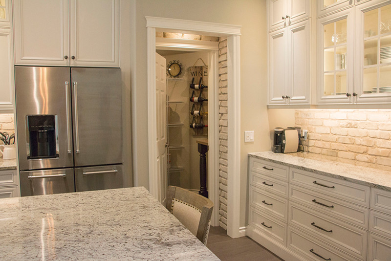 Eat-in kitchen - large transitional l-shaped eat-in kitchen idea with a double-bowl sink, shaker cabinets, white cabinets, beige backsplash, stainless steel appliances and an island