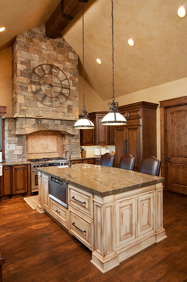 Example of a large mountain style dark wood floor kitchen design with an undermount sink, raised-panel cabinets, dark wood cabinets, granite countertops, beige backsplash, ceramic backsplash, paneled appliances and an island