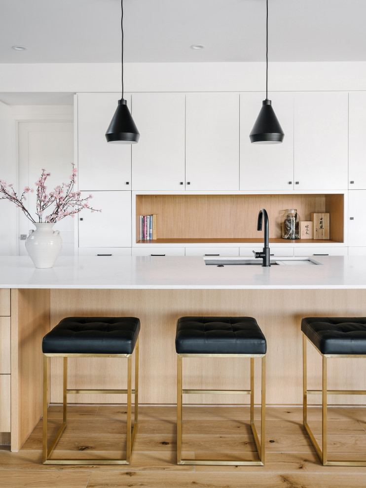 Large contemporary single-wall eat-in kitchen in Austin with an undermount sink, flat-panel cabinets, white cabinets, quartz benchtops, white splashback, ceramic splashback, stainless steel appliances, light hardwood floors, with island, beige floor, white benchtop and timber.