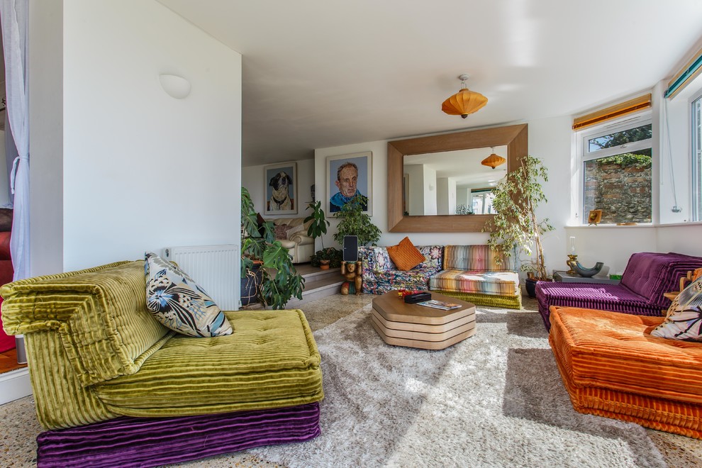 This is an example of an eclectic enclosed living room in Sussex with white walls and carpet.
