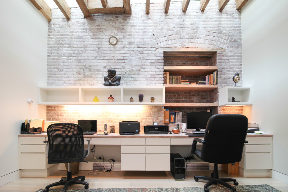 This is an example of a large contemporary study room in New York with white walls and a built-in desk.