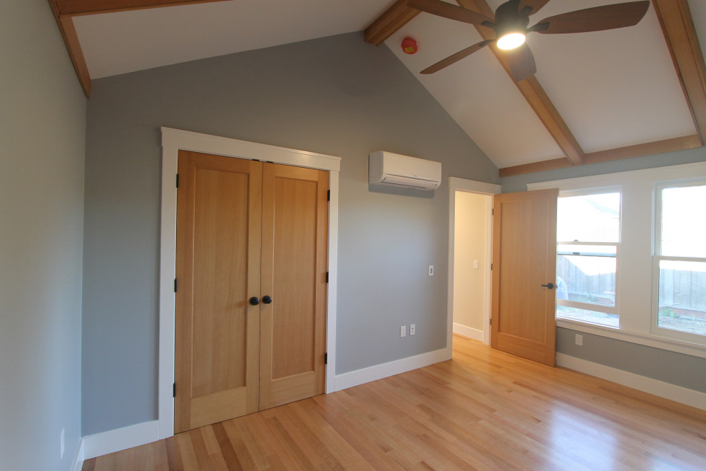 Ejemplo de dormitorio abovedado de estilo americano con paredes azules, suelo de madera en tonos medios y suelo marrón