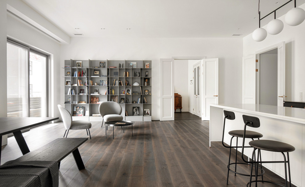 На фото: большая открытая, серо-белая гостиная комната в современном стиле с белыми стенами, темным паркетным полом и коричневым полом