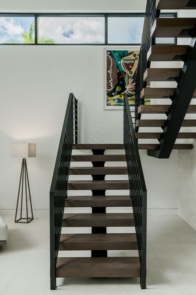 Imagen de escalera suspendida contemporánea de tamaño medio con escalones de madera, contrahuellas de madera y barandilla de metal