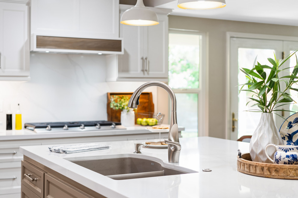Inspiration for a mid-sized transitional l-shaped ceramic tile, brown floor and exposed beam enclosed kitchen remodel with a double-bowl sink, shaker cabinets, white cabinets, quartz countertops, white backsplash, quartz backsplash, stainless steel appliances, an island and white countertops