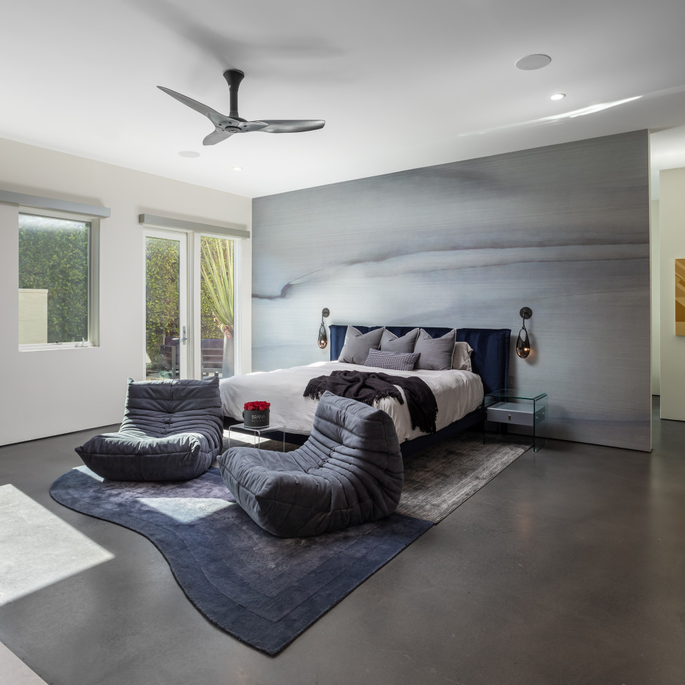 This is an example of a large contemporary master bedroom in Los Angeles with blue walls, concrete floors, a standard fireplace, a stone fireplace surround, grey floor and wallpaper.