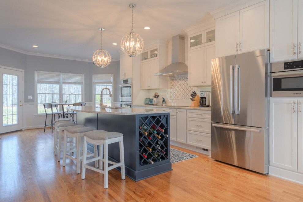 Inspiration for a mid-sized transitional galley medium tone wood floor eat-in kitchen remodel with an undermount sink, flat-panel cabinets, white cabinets, quartz countertops, white backsplash, subway tile backsplash, stainless steel appliances, an island and white countertops
