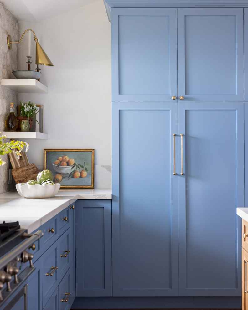 Immagine di un cucina con isola centrale con ante in stile shaker, ante blu, top in quarzo composito, paraspruzzi beige, paraspruzzi con piastrelle in pietra, elettrodomestici colorati e top bianco
