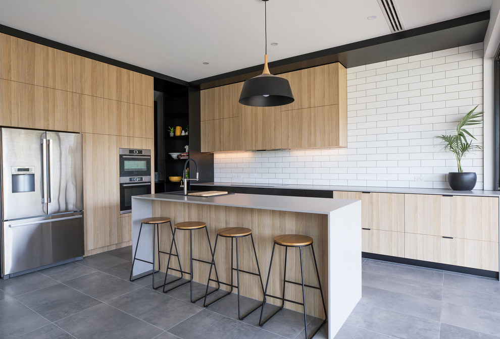 Inspiration for a mid-sized contemporary l-shaped kitchen pantry in Adelaide with a double-bowl sink, flat-panel cabinets, light wood cabinets, quartz benchtops, white splashback, subway tile splashback, stainless steel appliances, with island and grey floor.