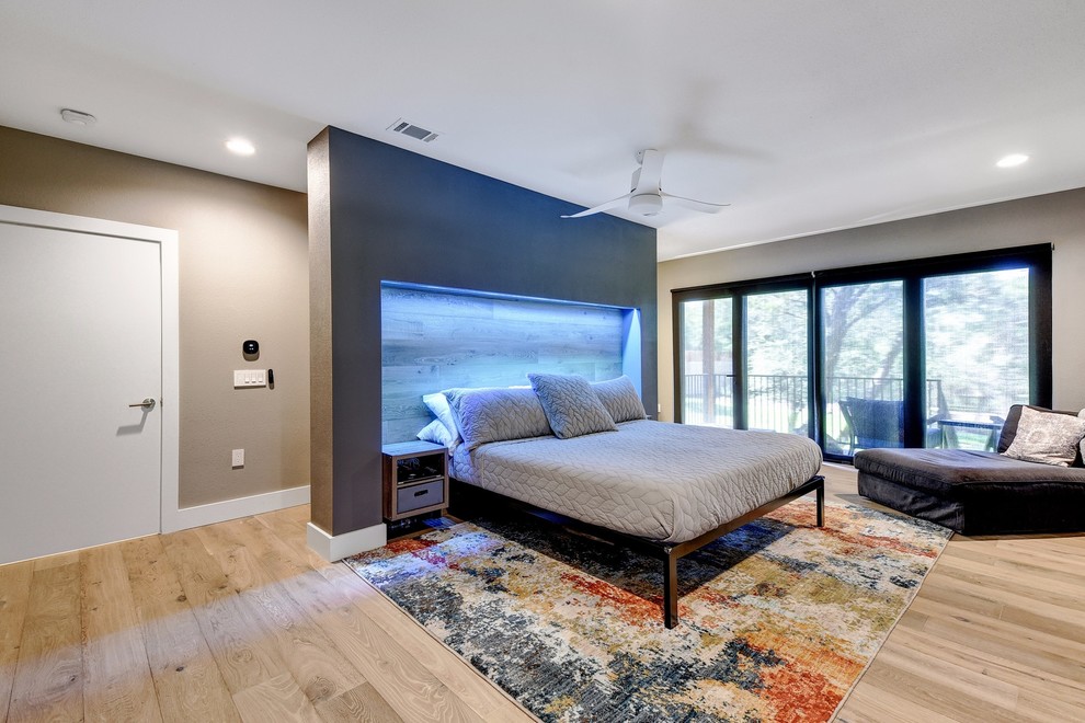 This is an example of a large modern master bedroom in Austin with grey walls, light hardwood floors and beige floor.