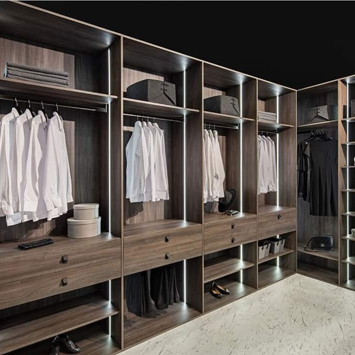Idée de décoration pour un grand dressing room minimaliste en bois foncé avec un placard sans porte.