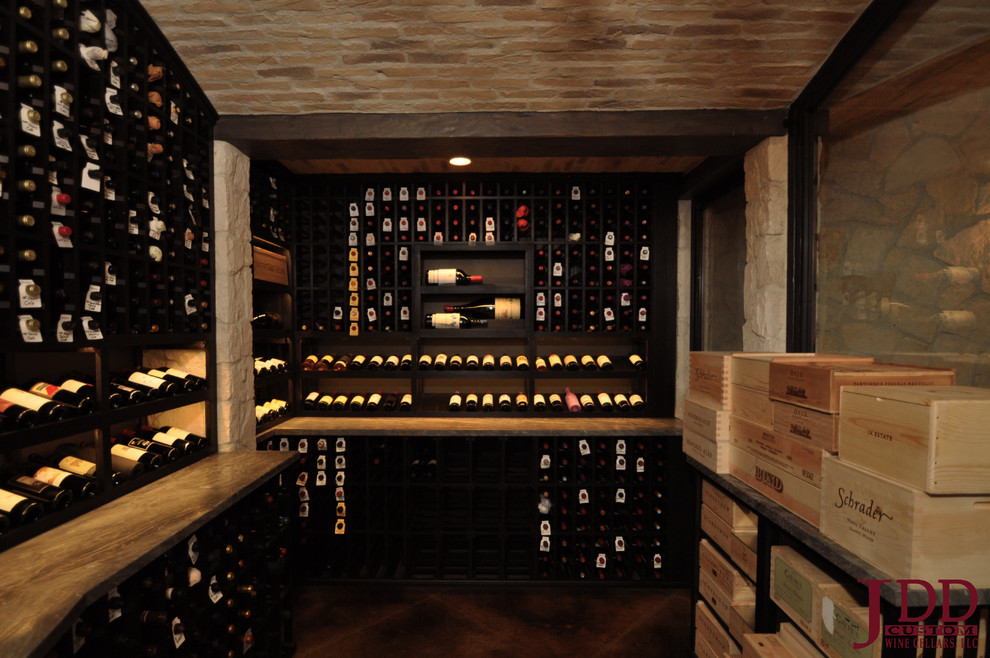 Photo of a large mediterranean wine cellar in San Diego with concrete floors and display racks.