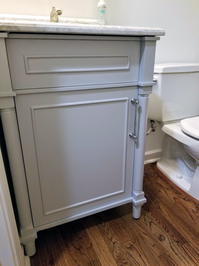 This is an example of a small transitional powder room in Atlanta with beaded inset cabinets, grey cabinets, white walls, medium hardwood floors, an undermount sink, marble benchtops, brown floor and grey benchtops.