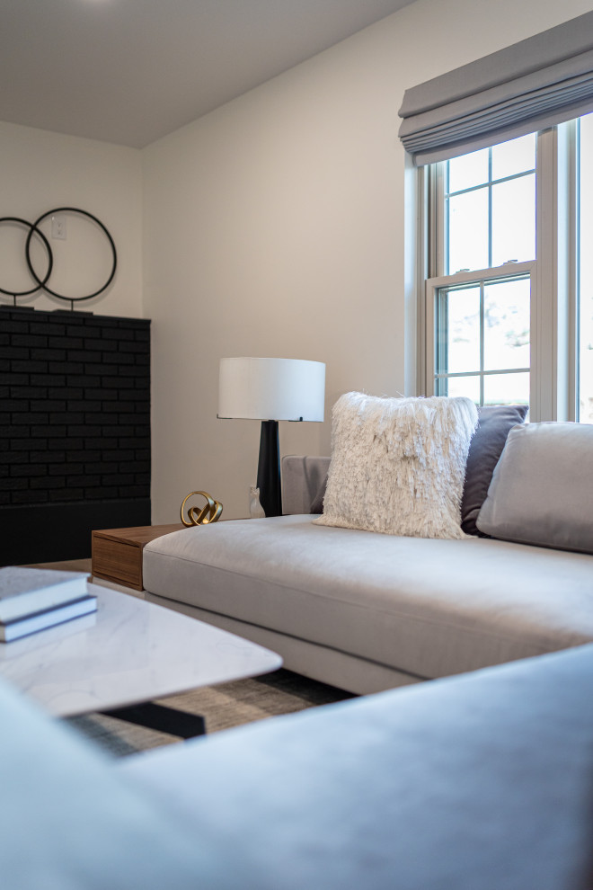 Foto di un ampio soggiorno moderno aperto con pareti bianche, parquet chiaro, camino classico, cornice del camino in mattoni e TV a parete