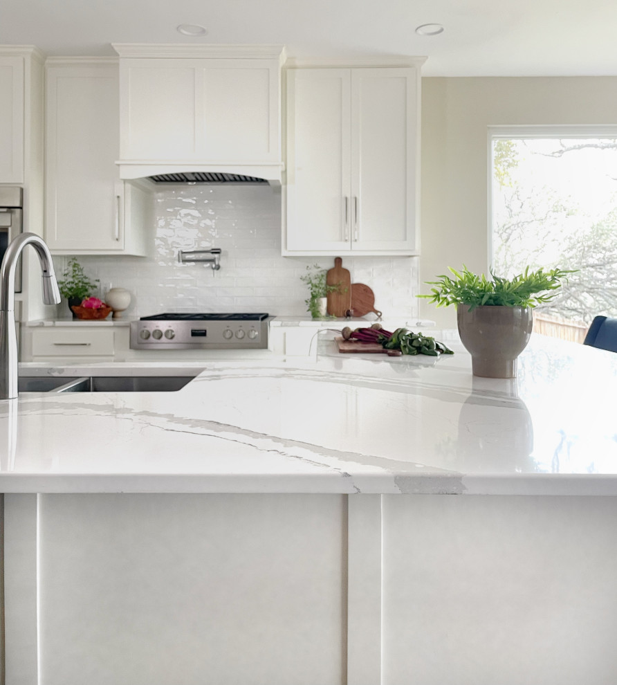 Example of a large ceramic tile and brown floor kitchen design in Austin with an undermount sink, shaker cabinets, white cabinets, white backsplash, subway tile backsplash, stainless steel appliances, an island and white countertops