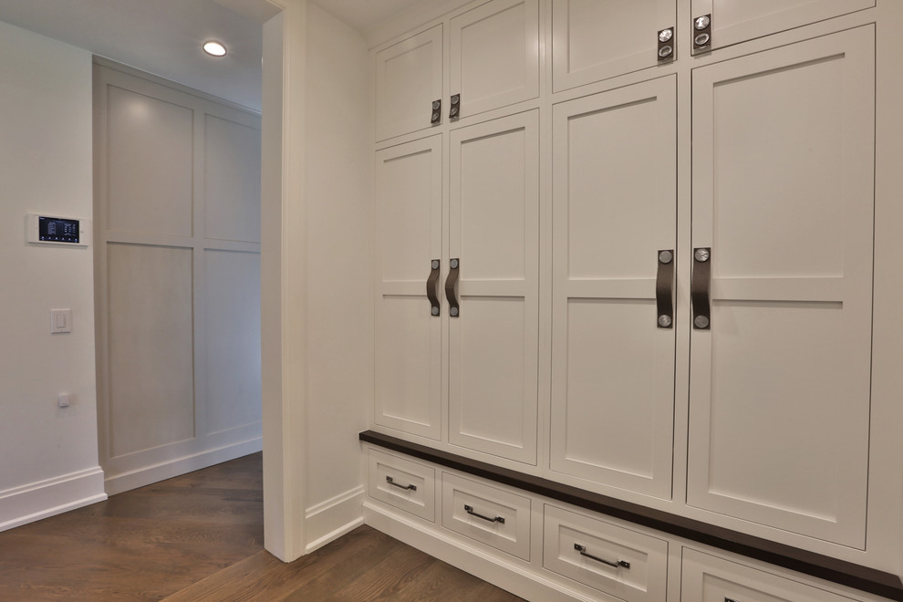 Inspiration for a large transitional gender-neutral storage and wardrobe in Columbus with beaded inset cabinets, white cabinets, medium hardwood floors and brown floor.