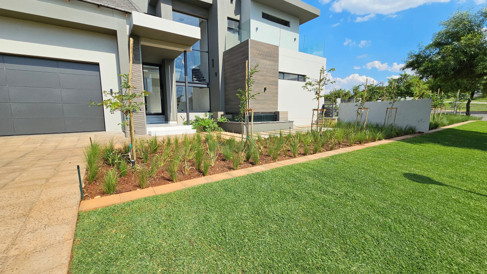 Idéer för en mellanstor modern formell trädgård i full sol längs med huset, med en stödmur och trädäck