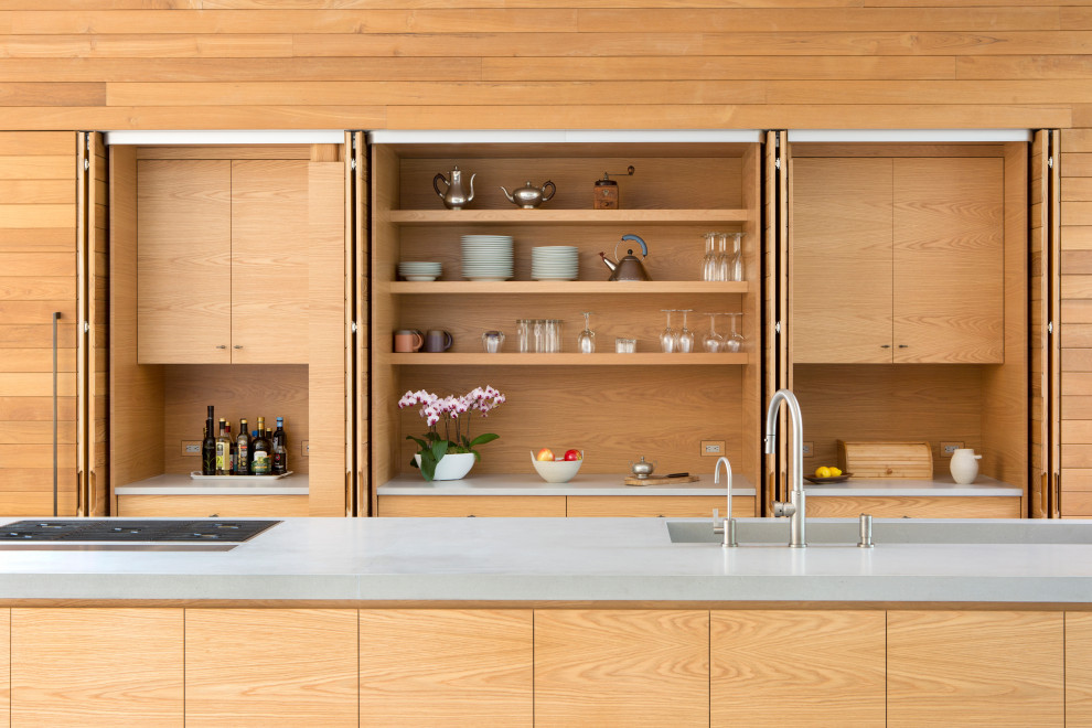 Exempel på ett mellanstort modernt grå linjärt grått kök med öppen planlösning, med en integrerad diskho, släta luckor, skåp i ljust trä, bänkskiva i kvarts, rostfria vitvaror, kalkstensgolv, en köksö och grått golv