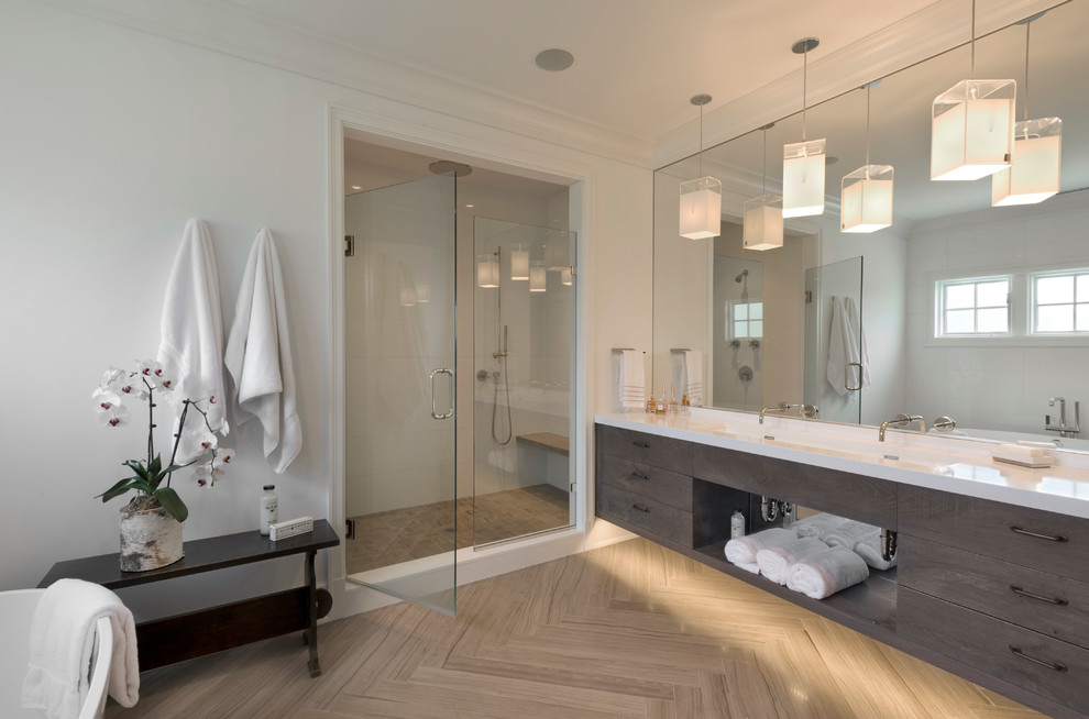 This is an example of a mid-sized contemporary master bathroom in New York with a trough sink, flat-panel cabinets, dark wood cabinets, an alcove shower, white walls, a freestanding tub, beige tile, stone tile, limestone floors and solid surface benchtops.
