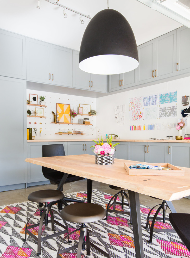 This is an example of an industrial craft room in Seattle with white walls, a freestanding desk and grey floor.