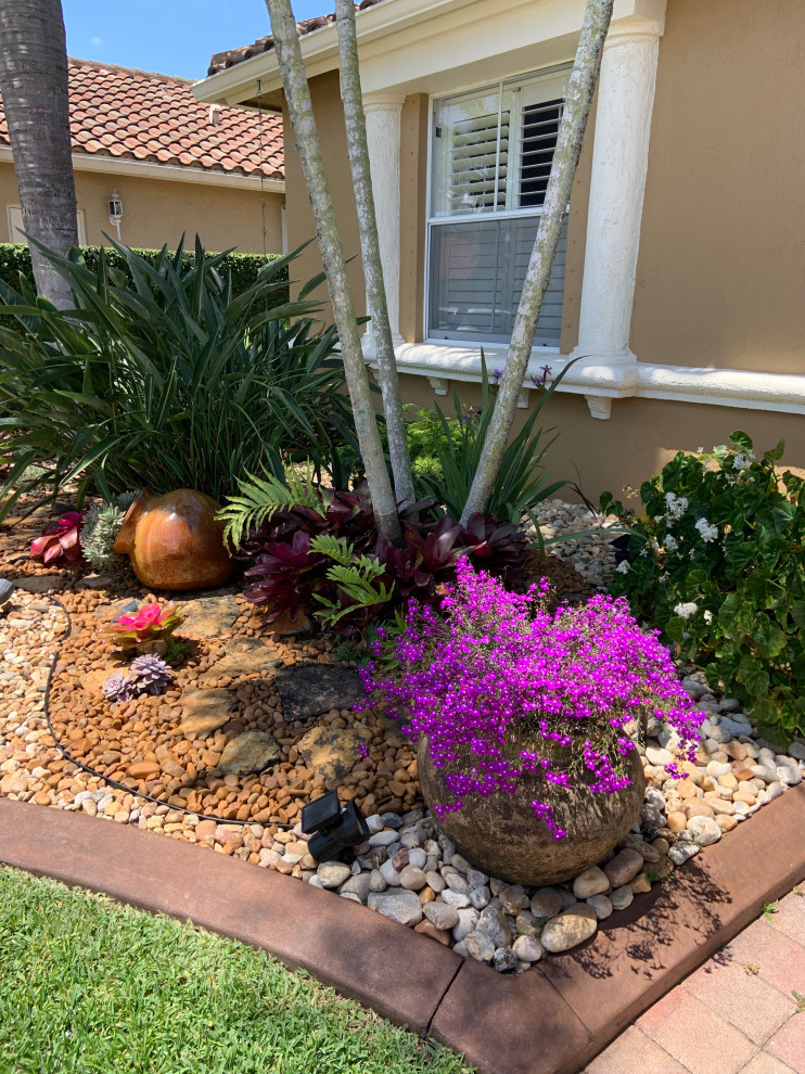 Design ideas for a tropical front yard xeriscape in Miami with river rock.