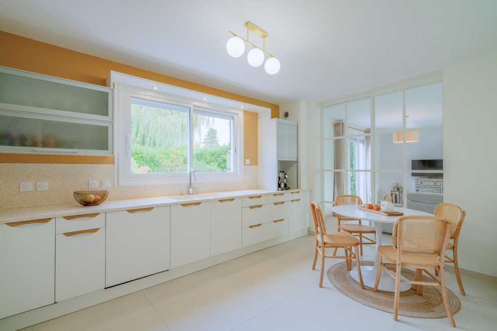 На фото: угловая кухня-гостиная в современном стиле с столешницей терраццо, разноцветным фартуком, бежевым полом, кессонным потолком и мойкой у окна