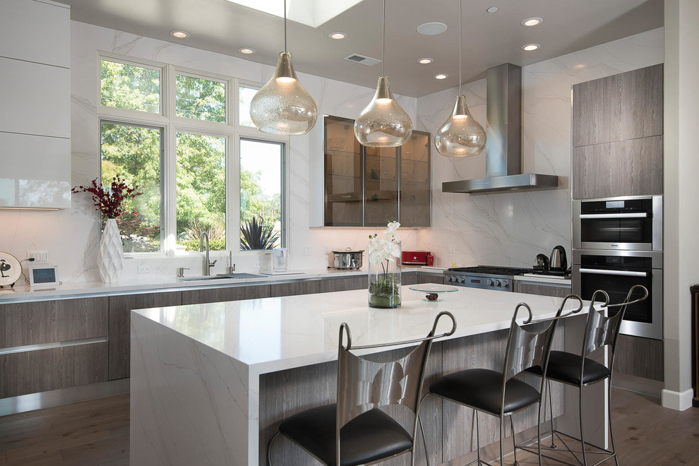 Inspiration for a contemporary l-shaped kitchen in San Francisco with an undermount sink, flat-panel cabinets, medium wood cabinets, white splashback, stainless steel appliances, medium hardwood floors, with island, brown floor and white benchtop.