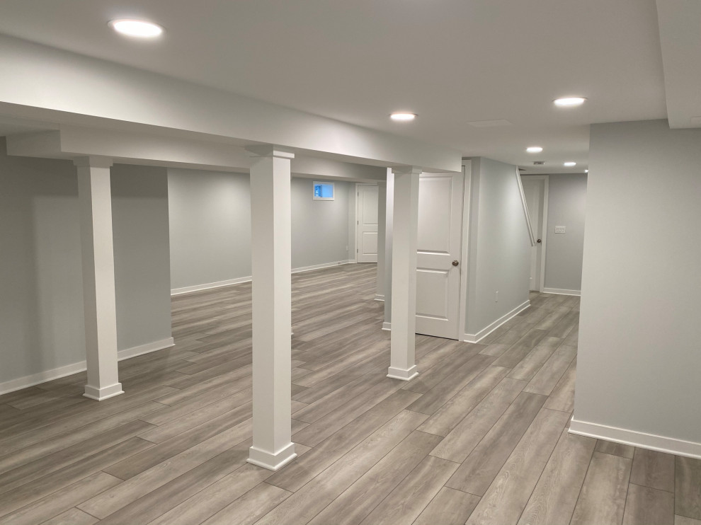 This is an example of a large contemporary walk-out basement in Philadelphia with grey walls, laminate floors and brown floors.