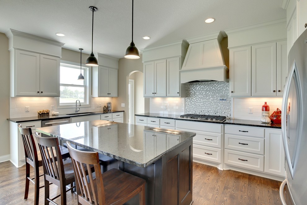 Large transitional u-shaped eat-in kitchen in Minneapolis with an undermount sink, recessed-panel cabinets, white cabinets, white splashback, subway tile splashback, stainless steel appliances, medium hardwood floors and with island.