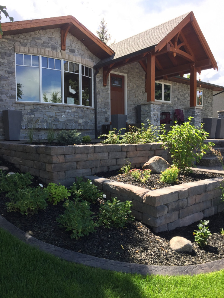 Design ideas for a mid-sized front yard formal garden in Calgary with with raised garden bed and natural stone pavers.