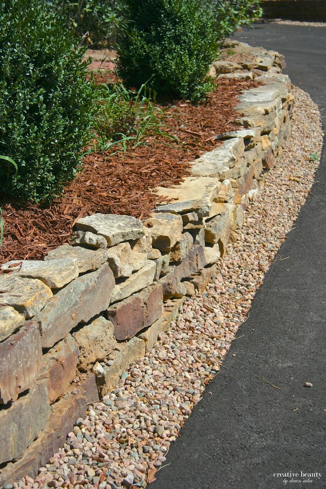 This is an example of a mid-sized backyard garden in Denver with a retaining wall and natural stone pavers.