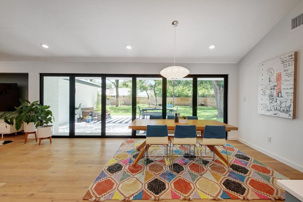 Esempio di una grande sala da pranzo aperta verso il soggiorno nordica con pareti bianche, parquet chiaro, pavimento marrone e soffitto a volta