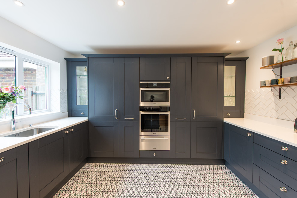 This is an example of a mid-sized contemporary eat-in kitchen in Hertfordshire with shaker cabinets, blue cabinets, quartzite benchtops and panelled appliances.