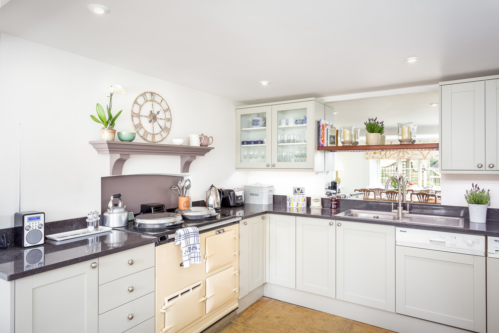 This is an example of a mid-sized country l-shaped eat-in kitchen in Gloucestershire with a drop-in sink, shaker cabinets, green cabinets, marble benchtops, grey splashback, panelled appliances, limestone floors and no island.