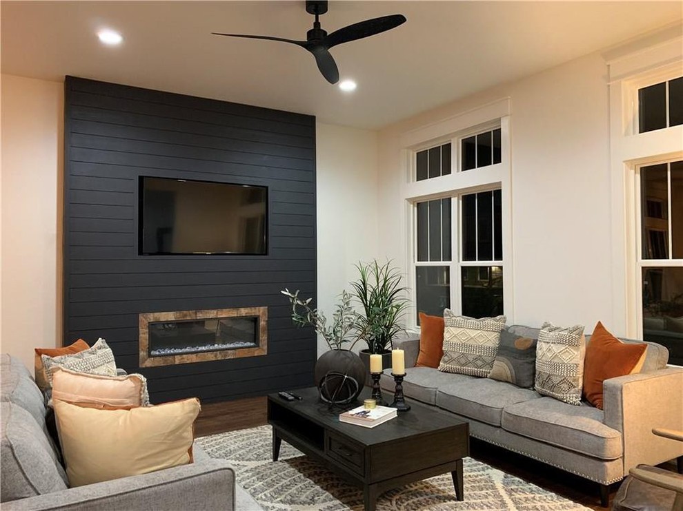 Inspiration for a mid-sized country formal open concept living room in Indianapolis with white walls, dark hardwood floors, a ribbon fireplace, a wood fireplace surround, a wall-mounted tv and brown floor.