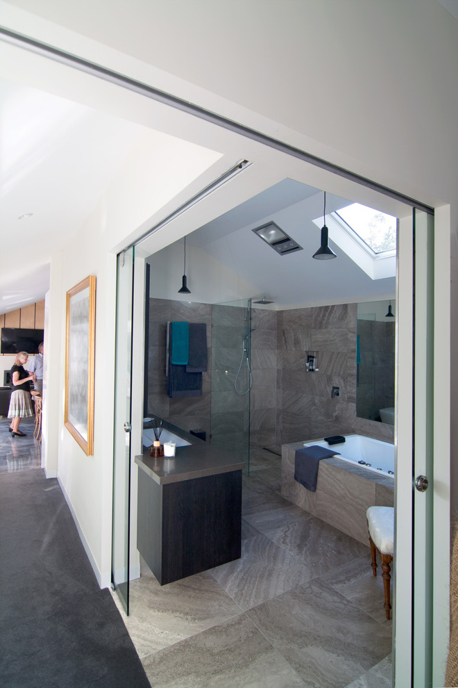 Inspiration for a large tropical master bathroom in Other with raised-panel cabinets, dark wood cabinets, a drop-in tub, an open shower, gray tile, stone tile, an undermount sink and engineered quartz benchtops.