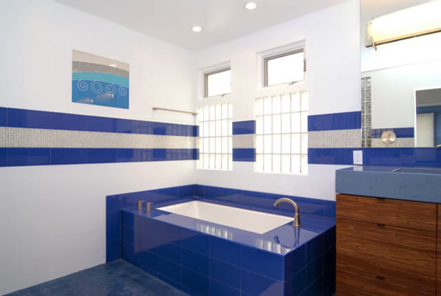 Mid-sized contemporary 3/4 bathroom in Orange County with flat-panel cabinets, dark wood cabinets, a drop-in tub, an open shower, a two-piece toilet, blue tile, white tile, glass tile, white walls, an integrated sink and solid surface benchtops.