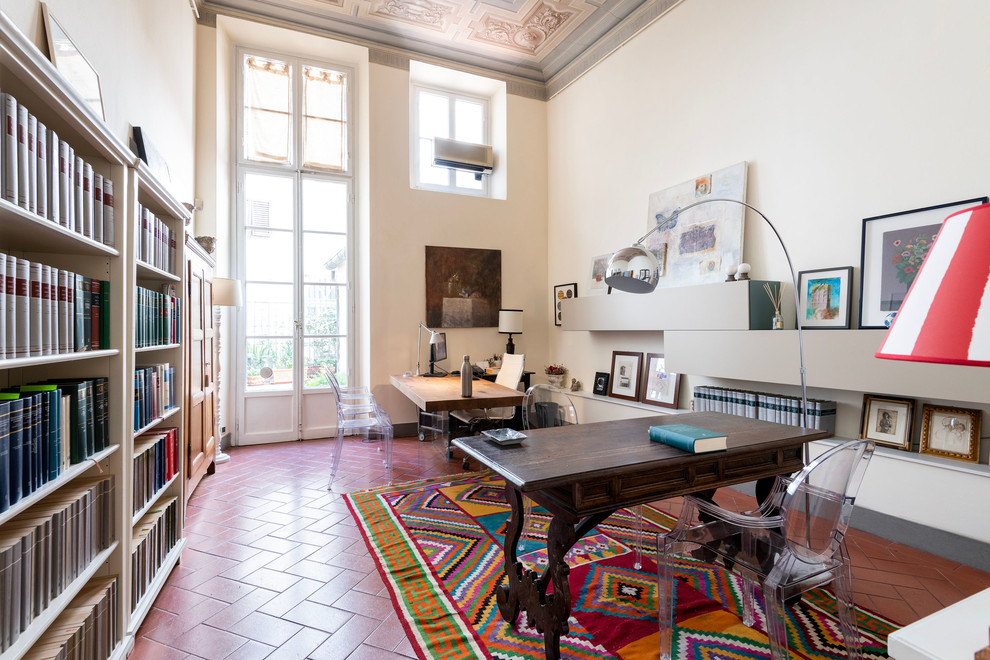 Large modern study room in Florence with white walls, terra-cotta floors, a standard fireplace, a concrete fireplace surround, a freestanding desk and brown floor.