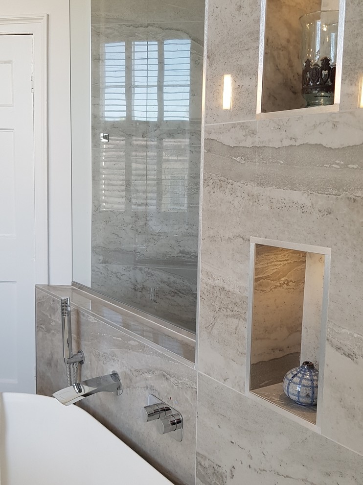 Inspiration for a large contemporary bathroom in Other with flat-panel cabinets, white cabinets, a freestanding bath, a wall mounted toilet, grey tiles, porcelain tiles, grey walls, porcelain flooring, a wall-mounted sink, marble worktops, grey floors, an open shower and white worktops.