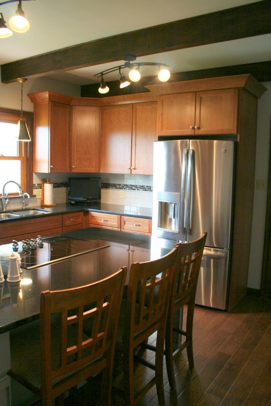 Inspiration for a mid-sized transitional l-shaped medium tone wood floor kitchen remodel with an undermount sink, recessed-panel cabinets, medium tone wood cabinets, granite countertops, white backsplash, ceramic backsplash, stainless steel appliances and an island