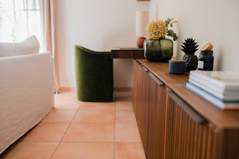 На фото: открытая гостиная комната среднего размера в средиземноморском стиле с бежевыми стенами, полом из терракотовой плитки, печью-буржуйкой и оранжевым полом