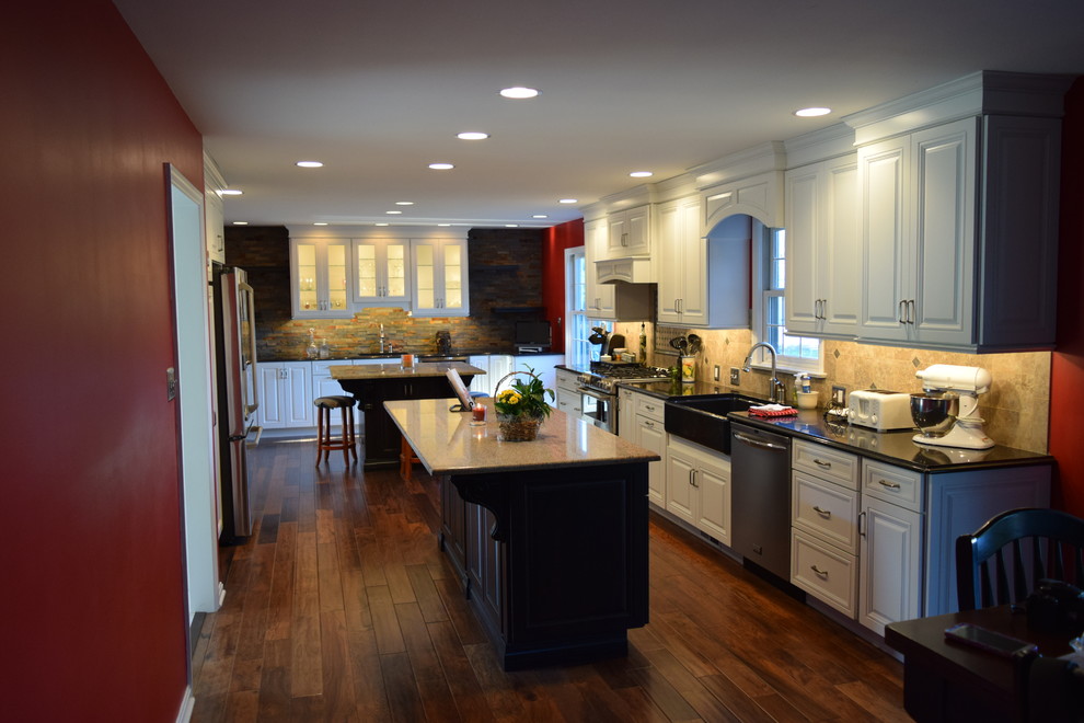 Transitional medium tone wood floor kitchen photo with a farmhouse sink, beaded inset cabinets, white cabinets, quartz countertops, beige backsplash, ceramic backsplash, stainless steel appliances and an island
