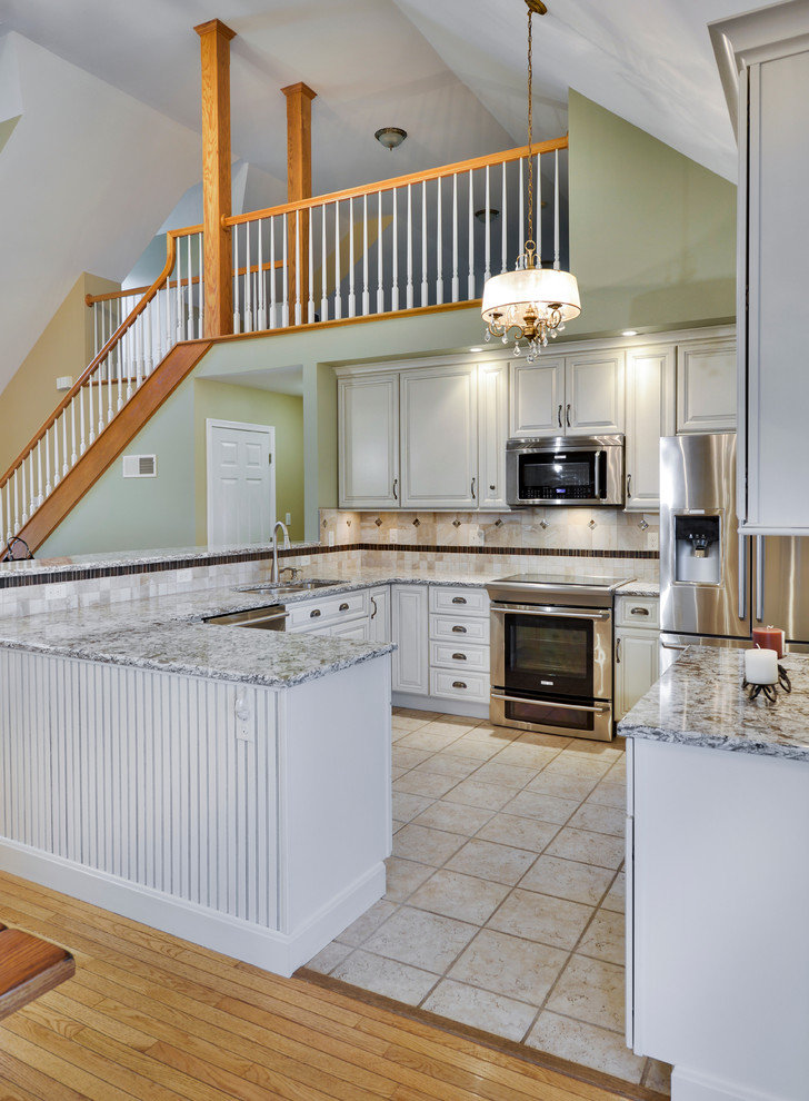 Mid-sized transitional galley open concept kitchen photo with a double-bowl sink, beaded inset cabinets, white cabinets, wood countertops, beige backsplash, ceramic backsplash, stainless steel appliances and a peninsula