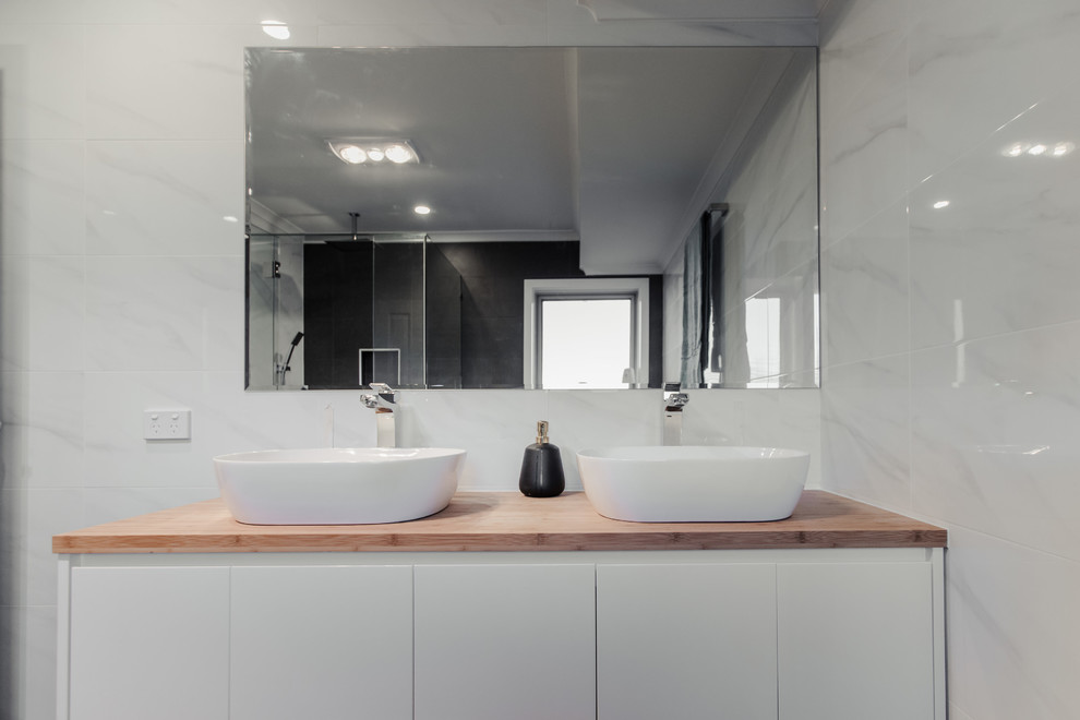 Mid-sized contemporary master bathroom in Adelaide with flat-panel cabinets, white cabinets, a freestanding tub, a corner shower, a two-piece toilet, white tile, ceramic tile, white walls, ceramic floors, a vessel sink, wood benchtops, grey floor and a hinged shower door.