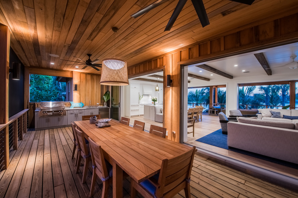 Tropical deck in Tampa with an outdoor kitchen and a roof extension.