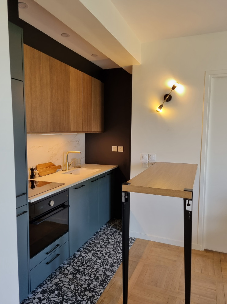 Photo of a small contemporary open plan kitchen in Paris with a submerged sink, flat-panel cabinets, green cabinets, composite countertops, beige splashback, ceramic splashback, black appliances, ceramic flooring, an island, black floors and beige worktops.