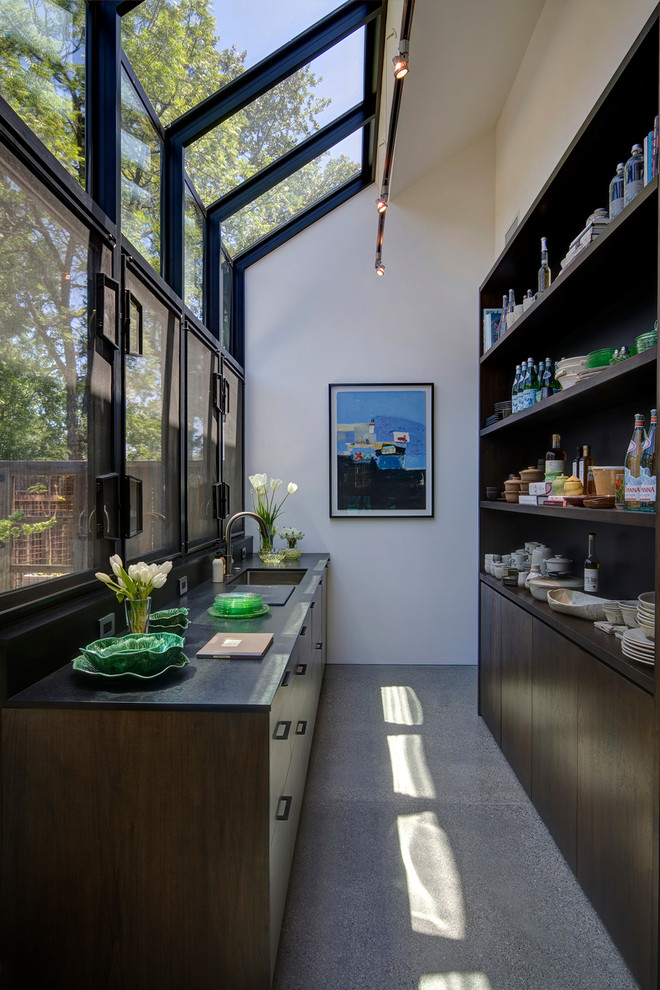 This is an example of a country kitchen in San Francisco with an undermount sink, dark wood cabinets, panelled appliances and concrete floors.
