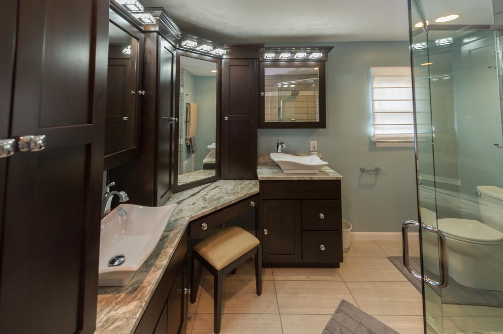 Mid-sized contemporary master bathroom in Indianapolis with a vessel sink, shaker cabinets, dark wood cabinets, granite benchtops, an alcove tub, a shower/bathtub combo, a two-piece toilet, gray tile, pebble tile, blue walls, porcelain floors, beige floor and a hinged shower door.